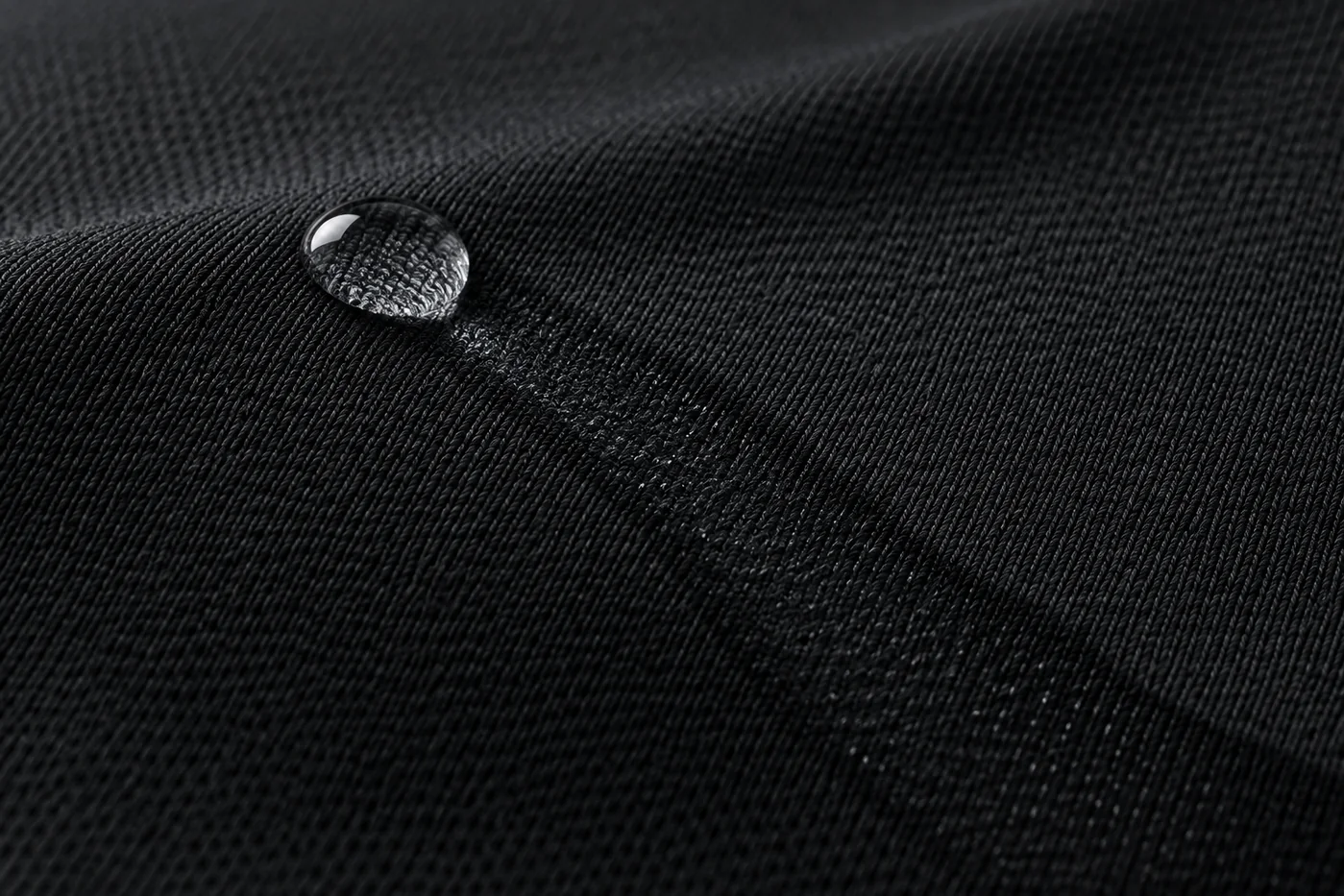 Black moisture-wicking quick-dry activewear knit with a water droplet spreading through the fabric structure